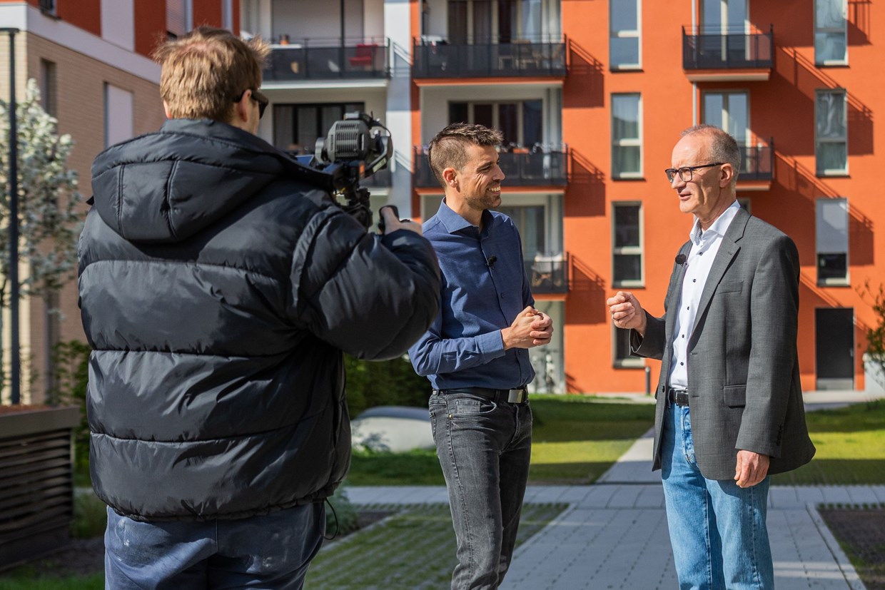 Zwei NHW Mitarbeiter unterhalten sich im sonnigen Schönhof-Viertel in Frankfurt und werden dabei von einer Filmcrew begleitet.