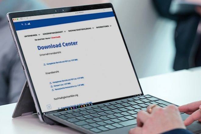 Ein Tablet mit einer Tastatur und einer tippenden Hand. Auf dem Tablet-Bildschirm ist das Download Center aufgezeigt.
