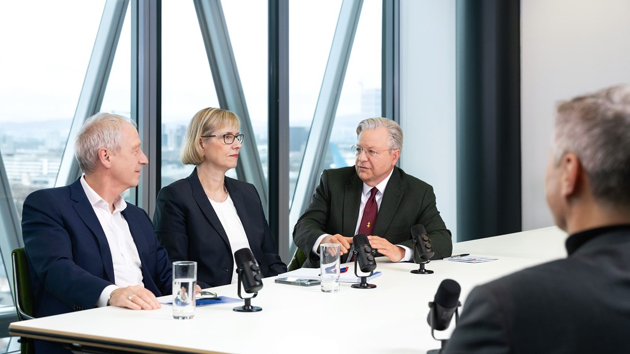 Die drei Geschäftsführenden der NHW sitzen an einem Konferenz-Tisch vor einer Fensterfront im Westhafe-ntower