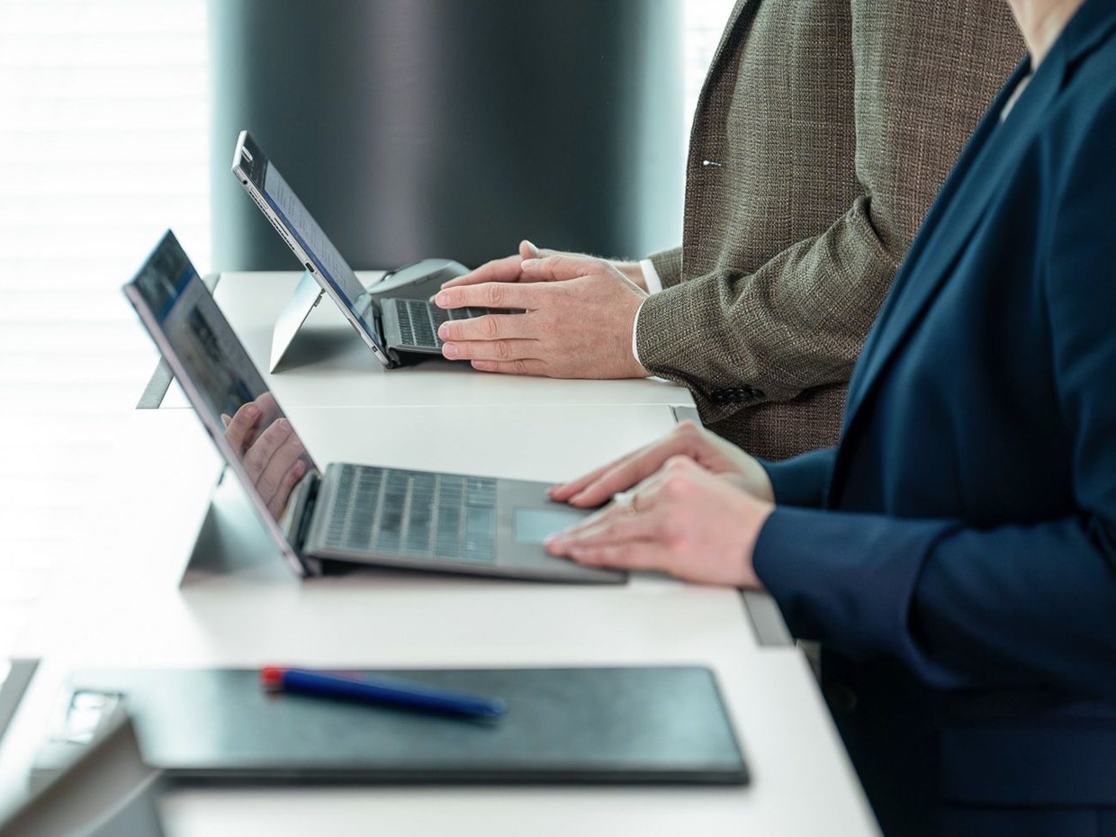 Nahaufnahme von den Händen zweier Mitarbeiter, die an einem Laptop arbeiten