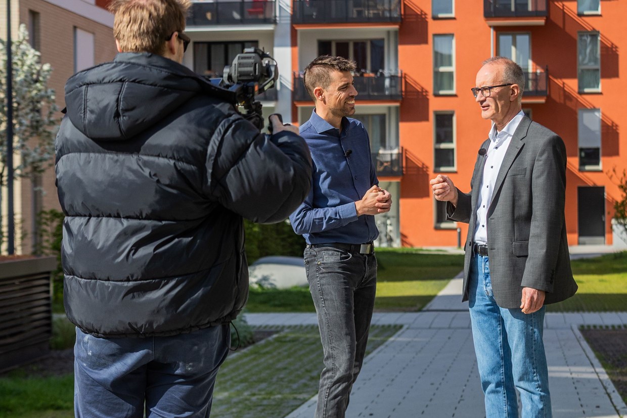 Zwei NHW Mitarbeiter unterhalten sich im sonnigen Schönhof-Viertel in Frankfurt und werden dabei von einer Filmcrew begleitet.